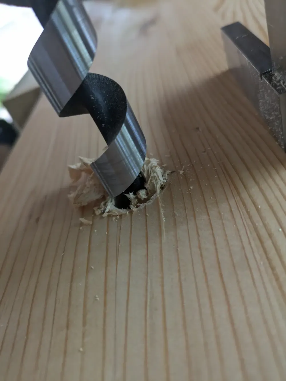 An auger bit aggressively tearing through the wood